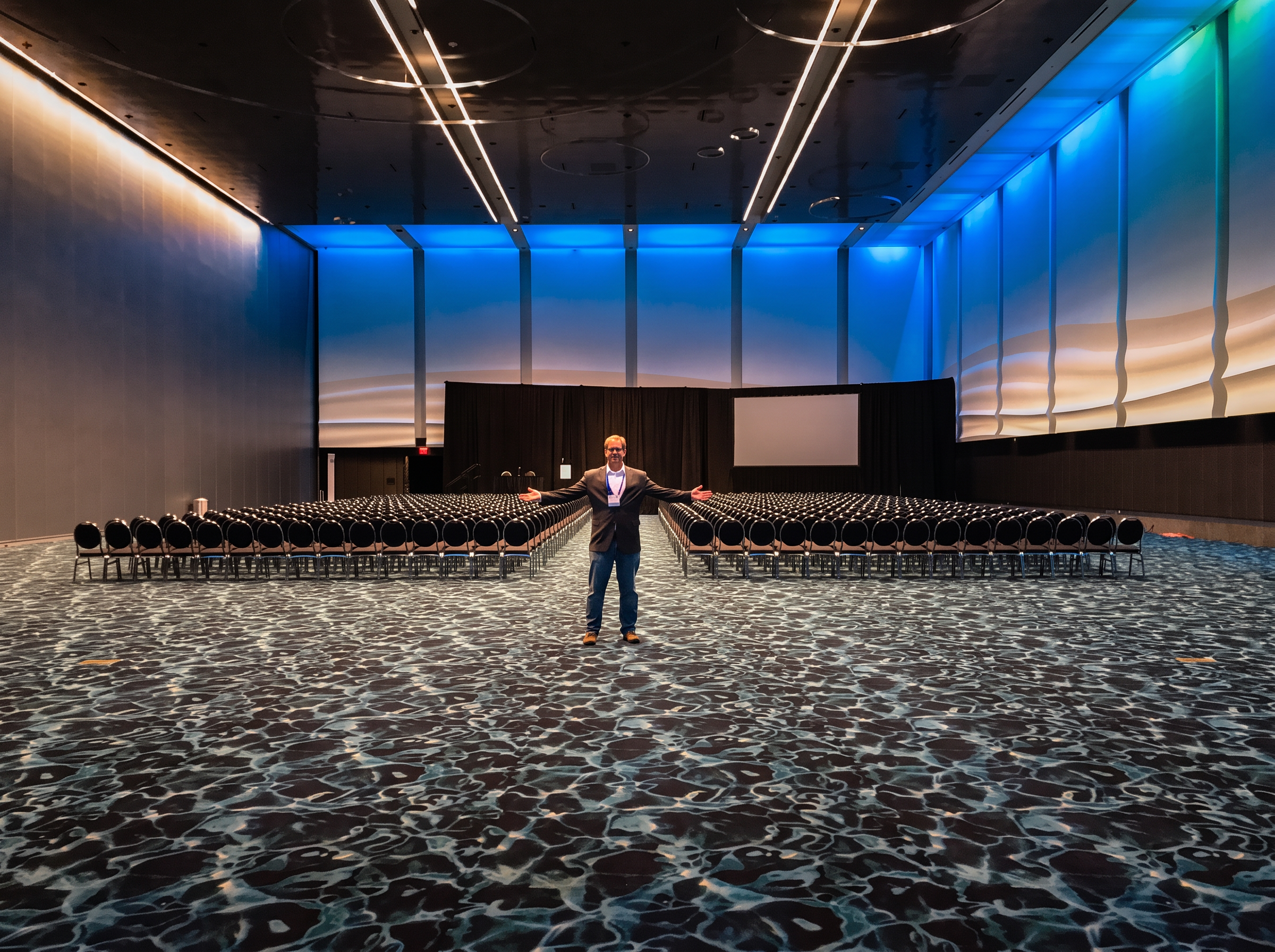 Trevor Dale standing in an empty ballroom set for a large conference audience